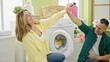 © Krakenimages.com - Man and woman couple washing clothes together high five at laundry room