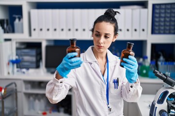 Sticker - Young caucasian woman scientist holding bottles at laboratory