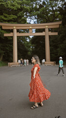 Poster - Joyful hispanic woman smiling with open arms, looking around at meiji temple, showcasing confidence and happiness