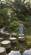 © Krakenimages.com - Beautiful hispanic woman's leisurely summer walk along stone path crossing a lake at traditional heian jingu shrine, kyoto