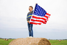 Young Boy Waving American Flag In Open Field