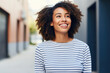 © pham - A woman with curly hair wearing a striped shirt smiles warmly.