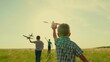 Children play run with toy airplane in their hand sunset. Boy child plays airplane pilot. Dream travel, fly. Children friends running with toy airplane, park grass. Childrens flight to future. Family