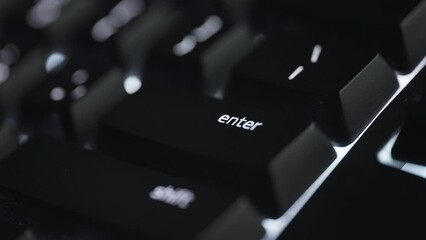 Pressing the enter button on black computer keyboard. Close up. 