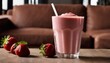 A glass of strawberry milkshake with strawberries on a table