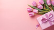 Top view photo of stylish pink giftbox with ribbon bow and bouquet of tulips on pink background with large copy space for message, Thank you, nature, Teache background, Friendship message