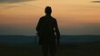 Silhouette of lonely soldier walking in field on red sunset background. A sad conceptual scene about the history of the soldiers of World War II and the Cold War.