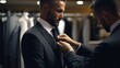 A man helping another man to adjust his tie in a suit shop. Perfect for illustrating the act of getting ready for a formal event or a professional setting