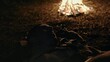Soldier sleeping on the ground near a blazing campfire at night in a close up view as he turns restlessly under his blanket