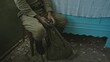 Soldier taking break from war in old house. Tilt up view of adult Soviet soldier taking flask from sack and looking out window while sitting at table in aged house and taking break during World War II