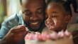 © Sophie - Father's Day african american  dad and daughter eating cake together. Candid special occasion dad and daughter bonding with cake. Messy cake food fight between father and daughter. Candid