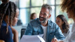 © Studio Nova - A bearded man in glasses enthusiastically discusses with colleagues during a team meeting at a vibrant office environment.
