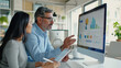 © MP Studio - Two professionals are engaged in a discussion over a computer displaying colorful analytical graphs, suggesting a collaborative business meeting or data review session.