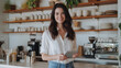 © MP Studio - young woman with a friendly smile, holding a tablet and standing in a modern kitchen or coffee shop.