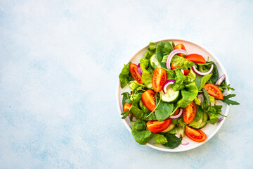 Wall Mural - Salad with green leaves and vegetables. Vegan food, diet meal. Top view with copy space at stone table.