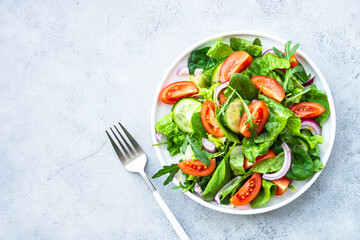 Wall Mural - Fresh green salad with leaves and vegetables. Top view with copy space at stone table.