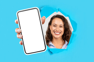 Poster - woman holding mobile phone in hand breaking through blue paper