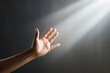 A man's hand reaches out to the rays of light against the background of a gray wall. Concept of spiritual life, support. Generated by artificial intelligence