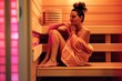 A woman sitting on a wooden bench in an infrared sauna room.