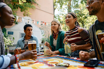 Wall Mural - Happy woman drinking cocktail while talking to her friends in cafe.