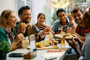 cheerful friends enjoying in mexican food in restaurant.