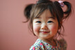 happy cute little asian baby girl with two ponytails on pink background, closeup smiling face