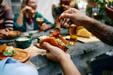 Wall Mural - Close up of man adding salsa sauce while eating tacos in restaurant.