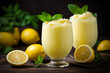 © fahrwasser - Refreshing lemon smoothie or slushie in tall glasses on dark background