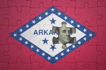 puzzle with the national flag of arkansas state and usa dollar banknote. finance concept