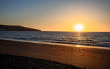 Fototapeta Desenie - Beautiful vibrant sunrise  reflected in the Atlantic Ocean on the coast of Fuerteventura Island, Tarajalejo beach in Canary Islands