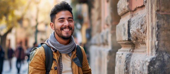 Poster - Happy young Hispanic man leaning on city wall, smiling.