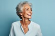 Beautiful senior woman with grey hair smiling and looking at camera on blue background
