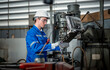© APchanel - Industry engineer worker wearing safety uniform control operating computer controlled Lathe grinding machine working in industry factory is metal manufacturing industry concept.