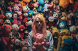 Scared girl woman with pink hair surrounded by creepy colorful stuffed animals toys and puppets