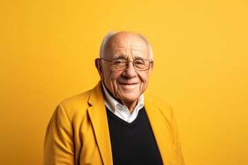 Portrait of a happy senior man with glasses on yellow background.