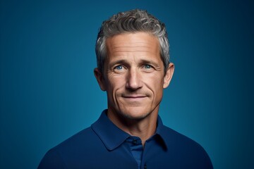 Wall Mural - Handsome middle-aged man with grey hair and blue shirt on blue background