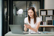 © laddawan - Beautiful woman using laptop and tablet while sitting at her working place. Concentrated