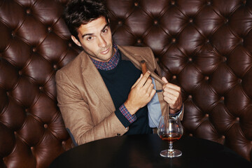 Portrait, cigar and businessman smoking at pub, fashion and serious person in a suit with alcohol at vintage bar. Face, mafia and drinking whiskey, scotch and brandy in a glass for luxury at club