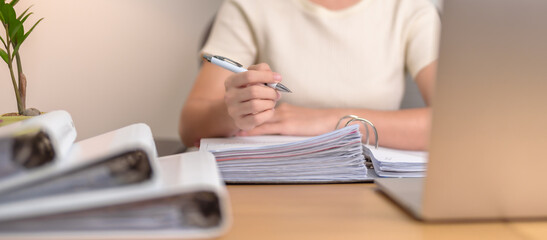 Asian woman working with computer laptop, female businesswoman reading report and sign contract with documents folder stack at home or office late night. Overworked, work hard and business concept