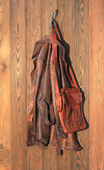 Wall Mural - old brown leather jacket on a hanger on a wooden wall