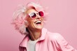 Fashionable young woman in pink wig and sunglasses on pink background
