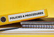 © Cagkan - Policies and procedures written on the label of a yellow binder on the office desk