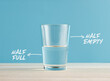 © Cagkan - Optimism and Pessimism concept. Water glass with the words half full and half empty.