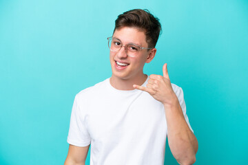 Wall Mural - Young handsome Brazilian man isolated on blue background With glasses and doing phone gesture