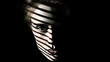 A persons face is partially illuminated with dramatic shadows casting striped patterns across the skin creating a mysterious and intense mood