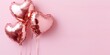 heart shaped rose gold foil balloons on left side with pastel pink copy space background