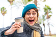 Brunette woman holding a take away coffee at outdoors with surprise and shocked facial expression