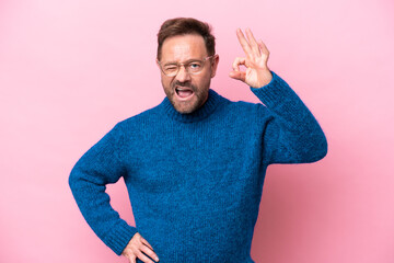 Wall Mural - Middle age caucasian man isolated on pink background showing ok sign with fingers