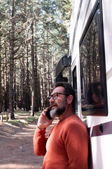 Wall Mural - Travelers man standing outside a modern motorhome camper van enjoying destination in nature forest woods. People and vehicle travel rv lifestyle. Vanlife. Alternative home and vacation holiday people