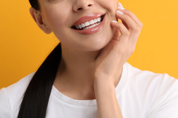 Wall Mural - Woman with clean teeth smiling on yellow background, closeup